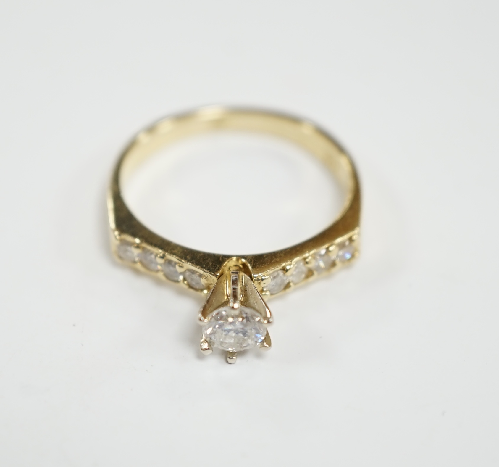 A modern 14k and single stone diamond set ring, with diamond chip set shoulders, size M, gross weight 2.7 grams.